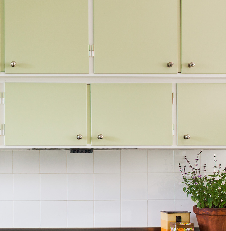 Ljusgrönt måttbyggt kök med förnicklade knoppar.