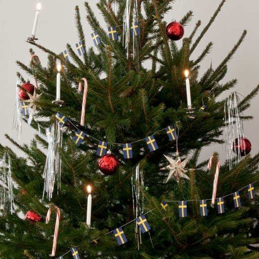 gammaldags julgran klädd med flaggirlanger och levande ljus