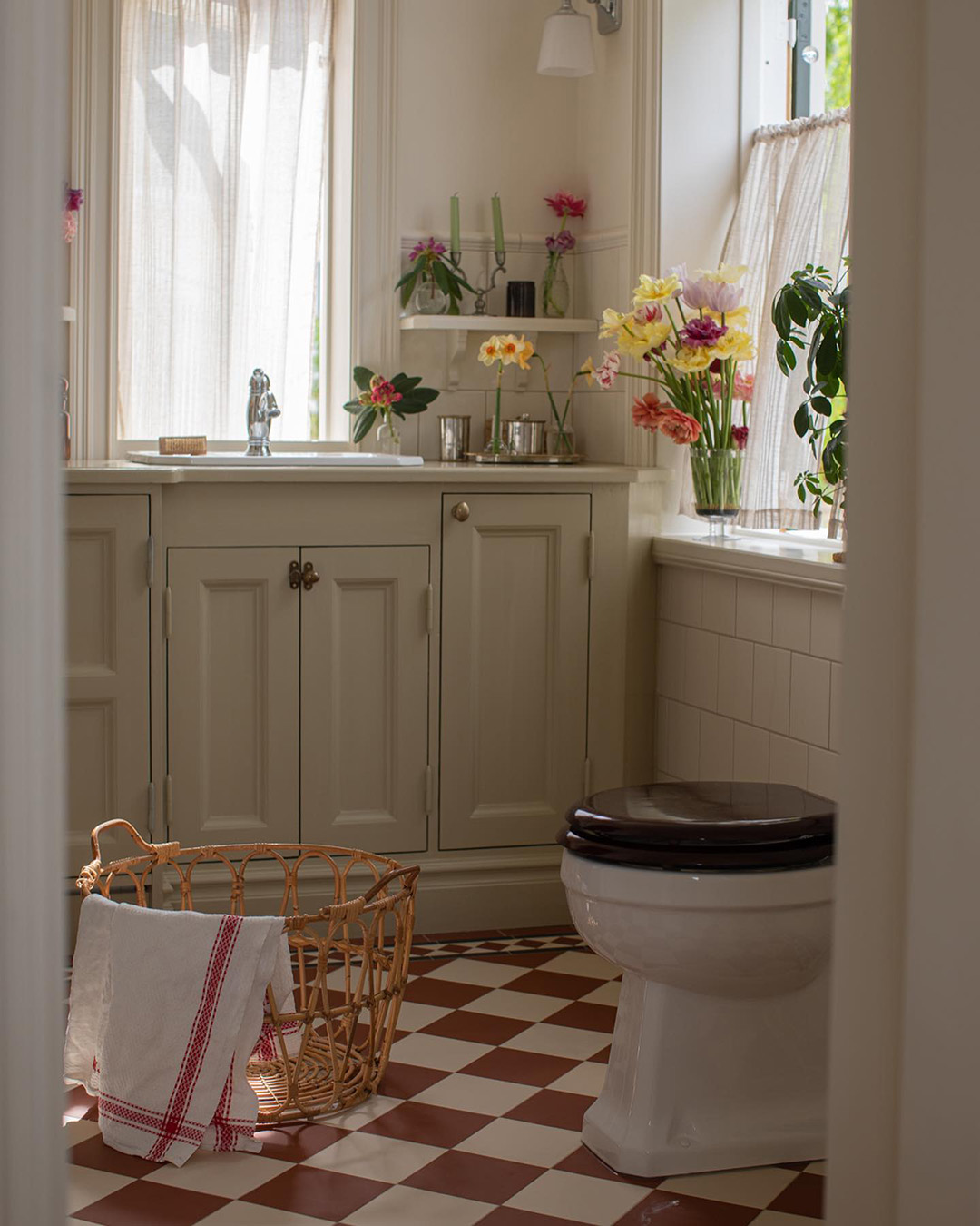 Lantligt badrum med platsbyggd inredning i trä med rödvitrutigt klinkergolv.