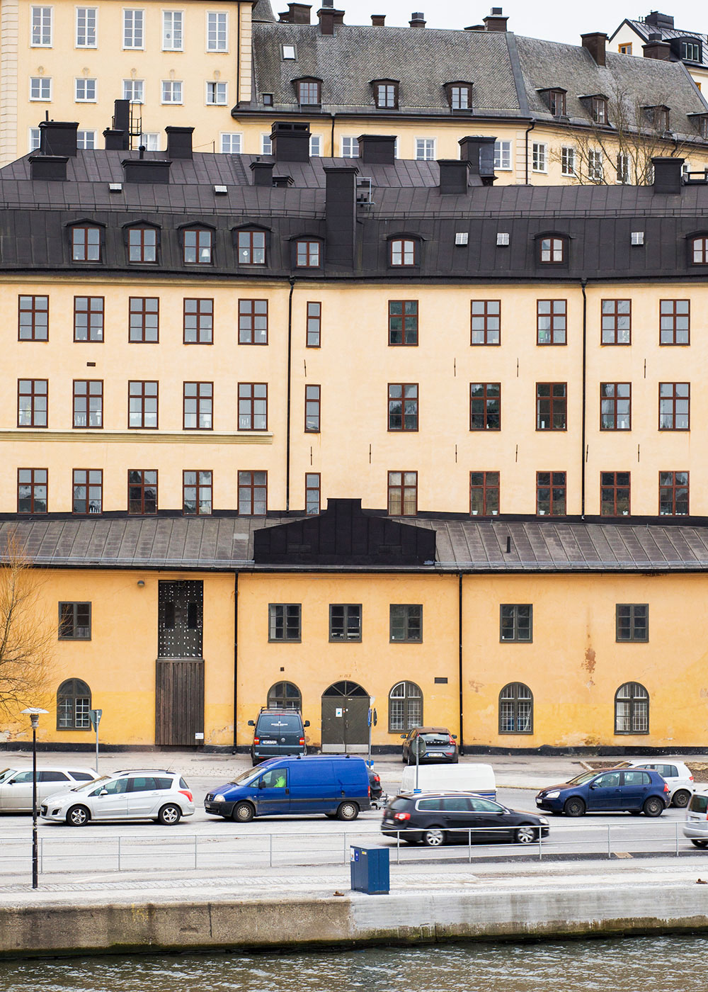 Ljusgult putsat hus med röda träfönster.