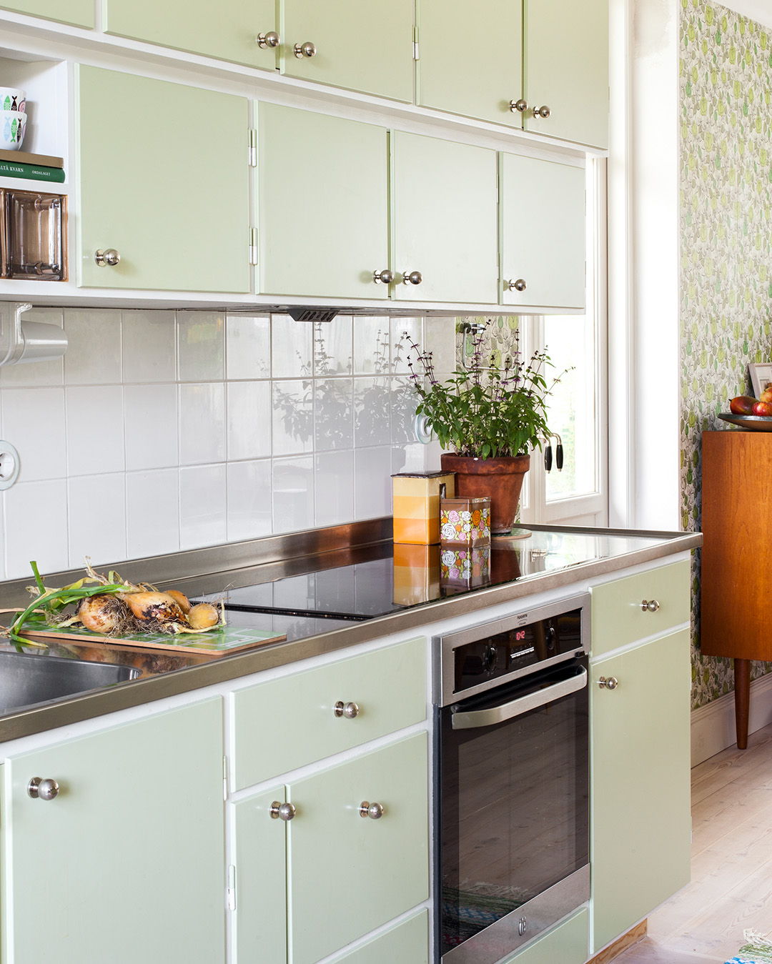 Måttbyggt kök målat i ljusgrön kulör med knopp Ribershus i förnicklad mässing.