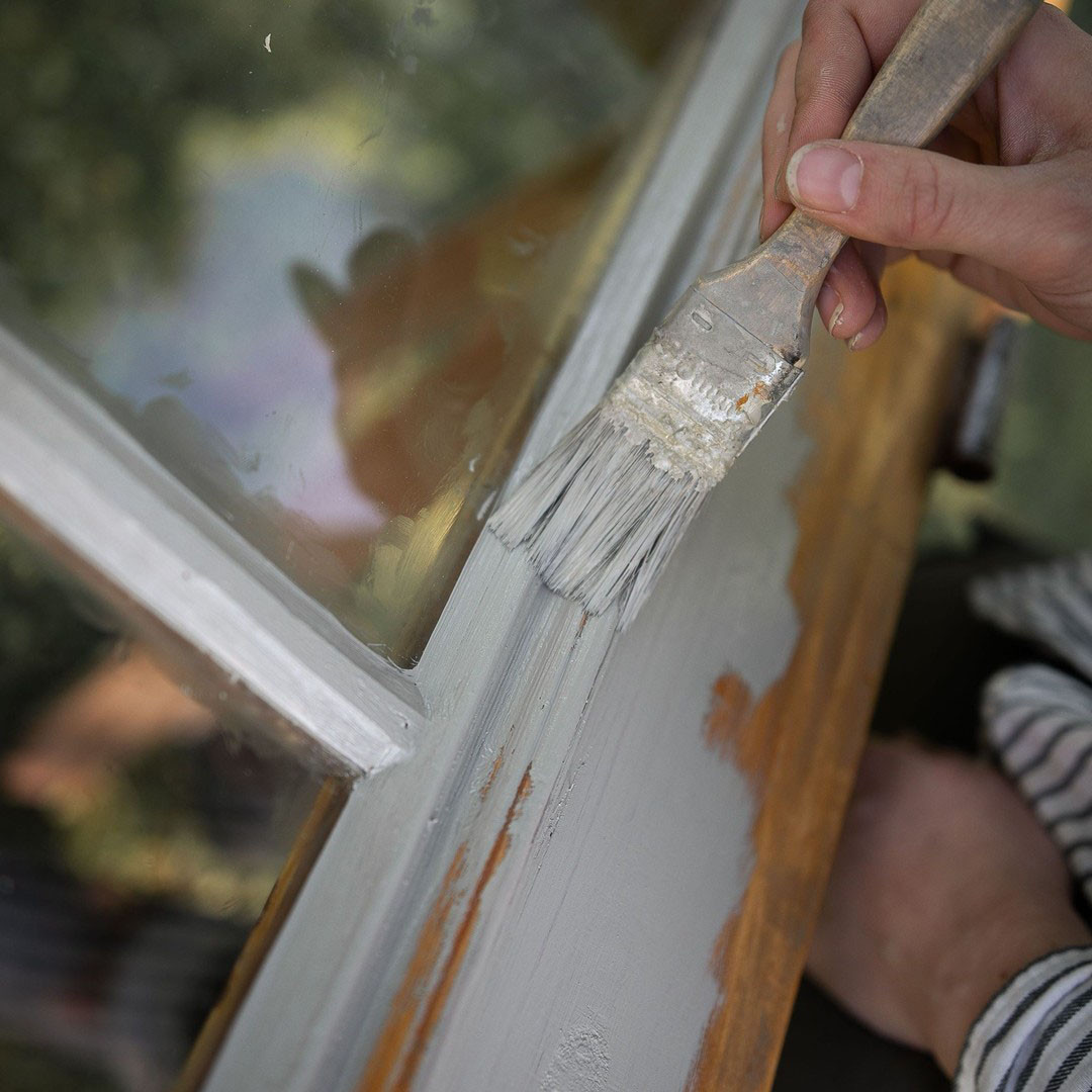 Fönster som målas med en mellangrå linoljefärg.