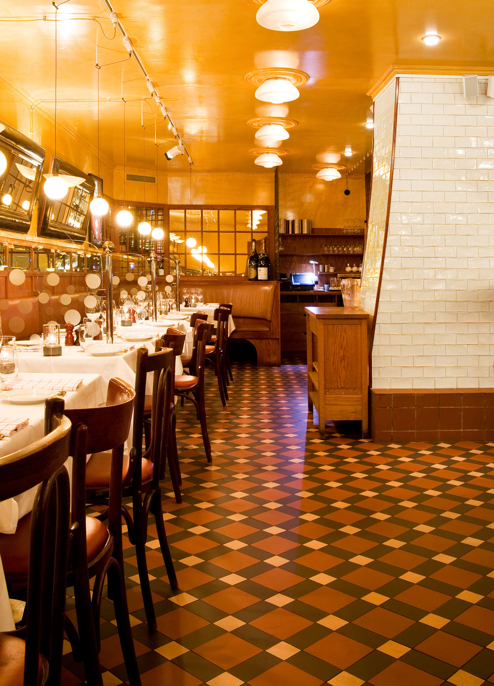 Restaurangdel med bord med vita dukar och trästolar på klinkergolv av Victorian Floor Tiles.