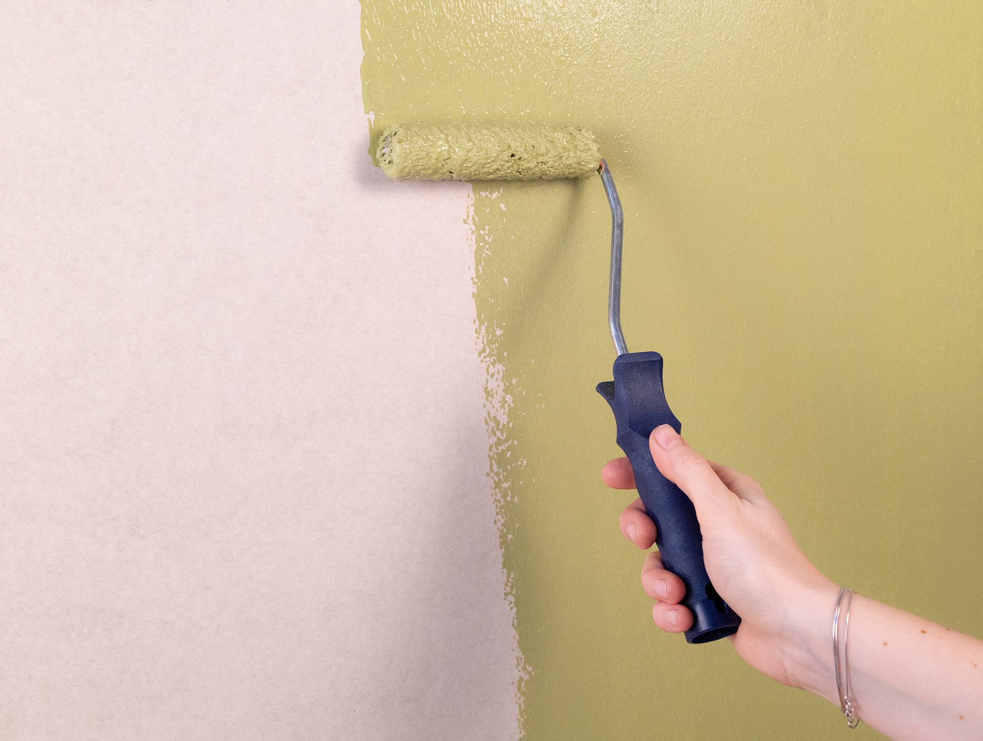 Hand som rollar del av vägg med en pistagegrön färg.