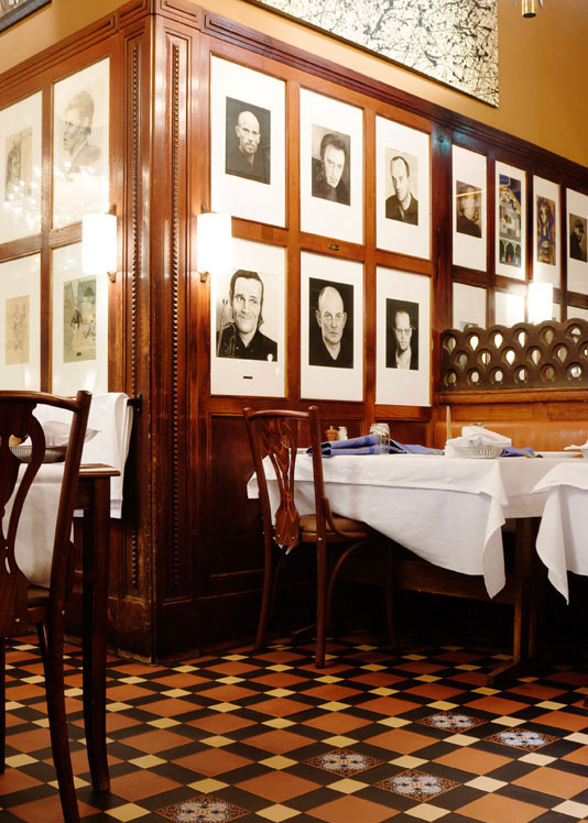Restaurangdel med bord med vita dukar på ett mönstrat klinkergolv av Victorian Floor Tiles.