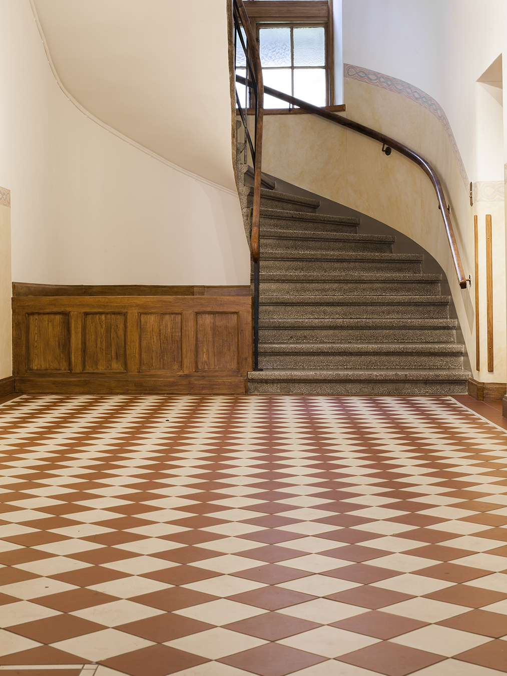 Trapphus med golv av klinker i mönster Flensburg i vit och röd lagd på diagonalen.